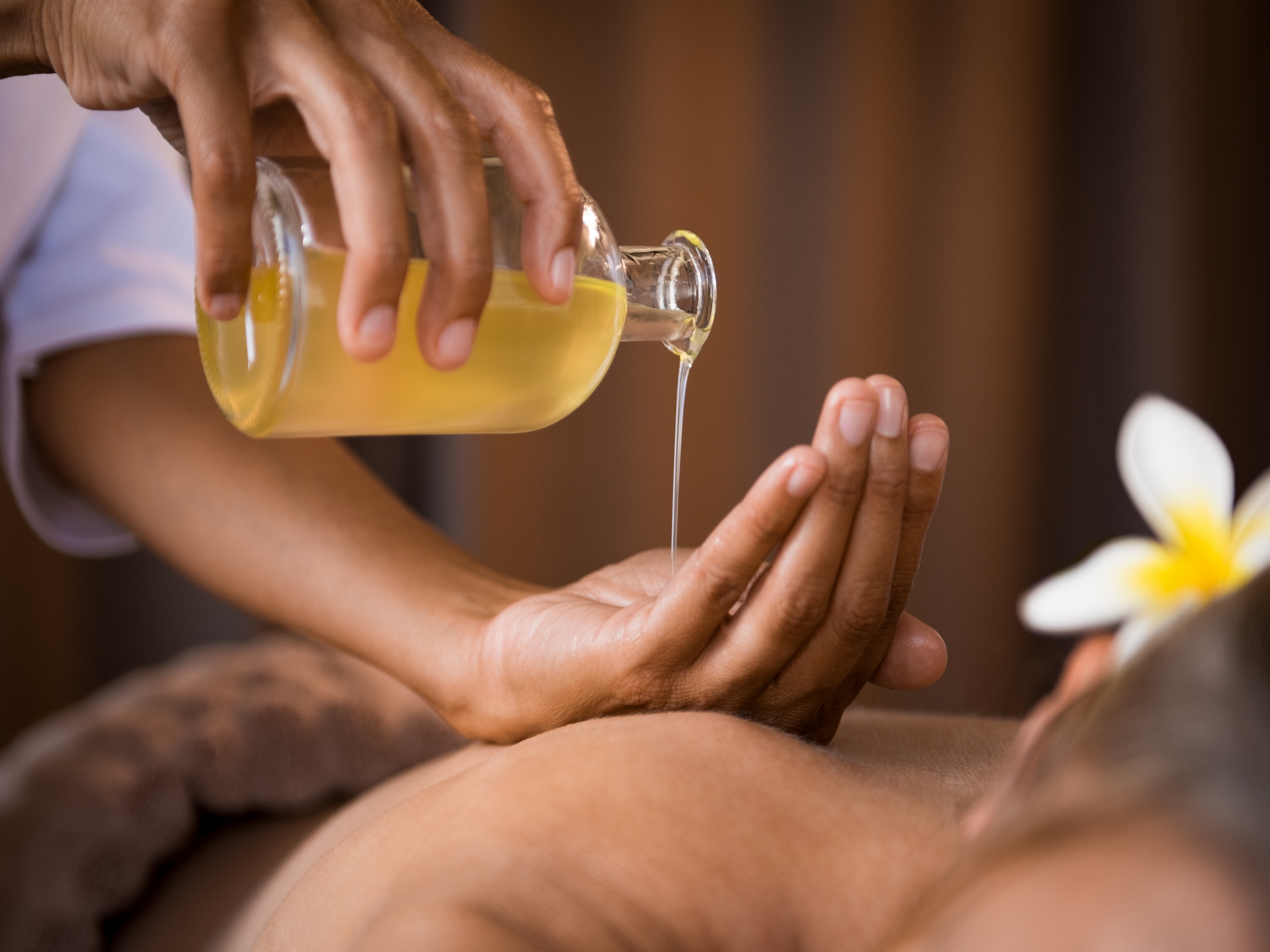 Closeup of masseur hands pouring aroma oil on woman back. Masseuse prepare to do oriental spa procedure for relaxing treatment. Therapist doing aromatherapy oil massage on woman body.