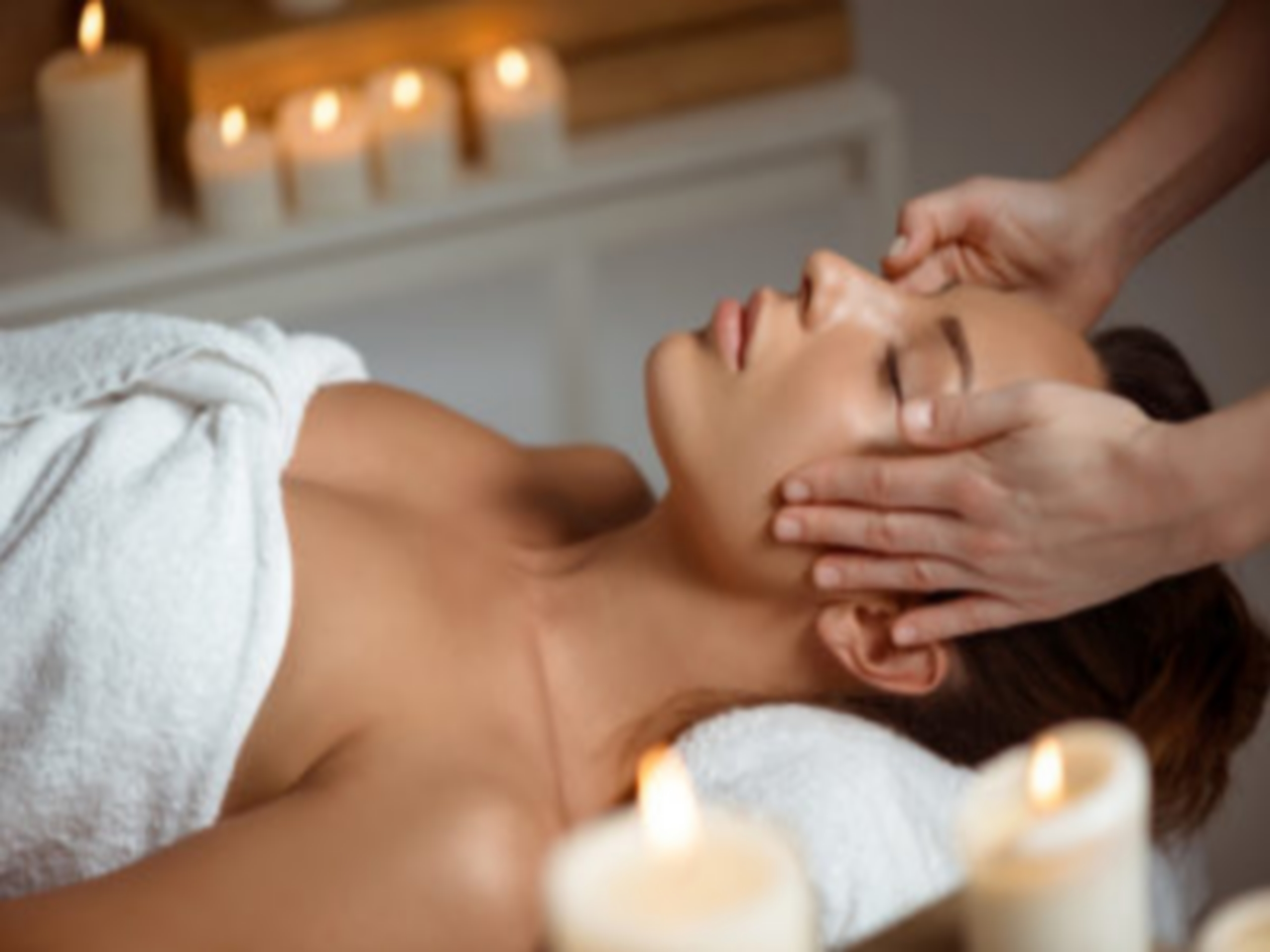 Young beautiful brunette girl having face massage relaxing in spa salon. Eyes closed. Copy space.